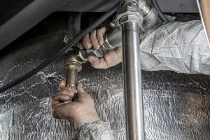 Vodoinstalater popravlja cevi da bi se sprečila poplava u stanu